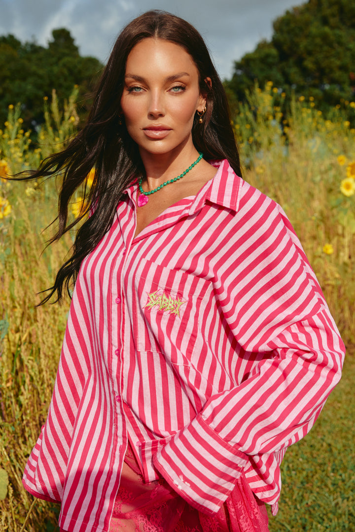 Person standing in sunflower field wearing red and pink striped Don Julio Shirt.