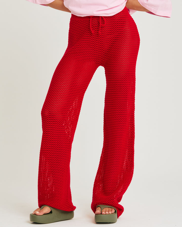 Person standing in photo studio wearing red knit pants.