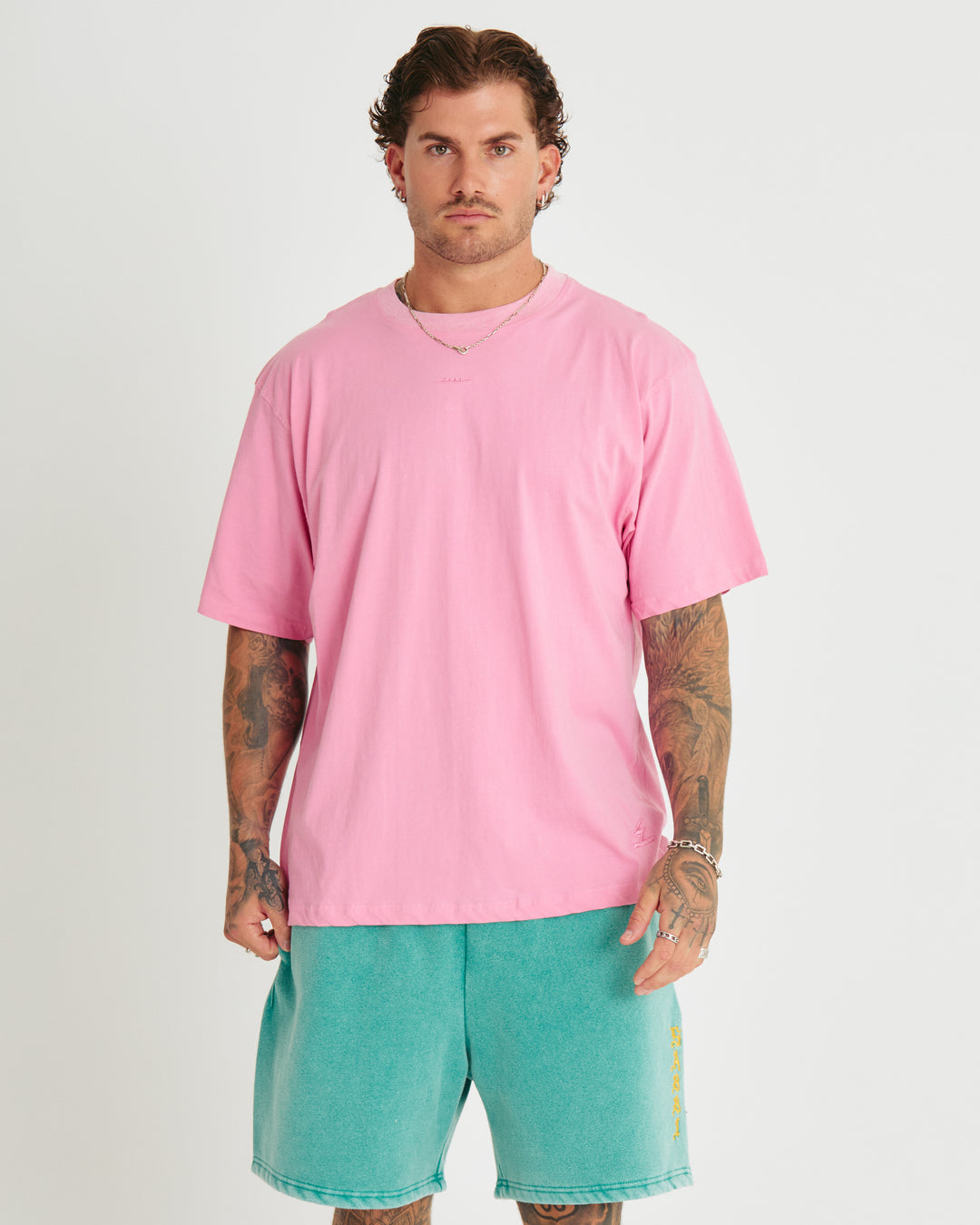 Person standing in photo studio wearing bright pink Very Oversized Basic Tee