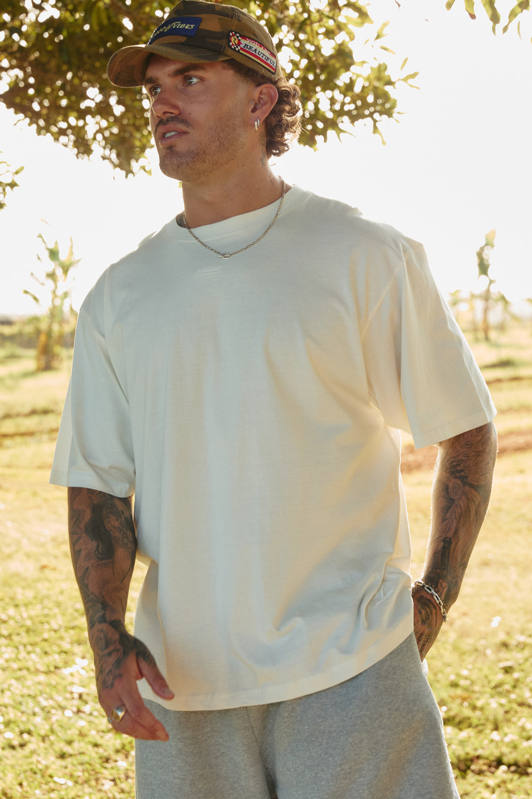 Person standing in a park wearing off white Very Oversized Basic Tee