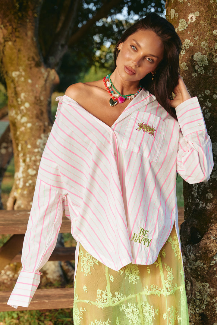 Person standing in front of a tree wearing white and pink striped Don Julio Shirt