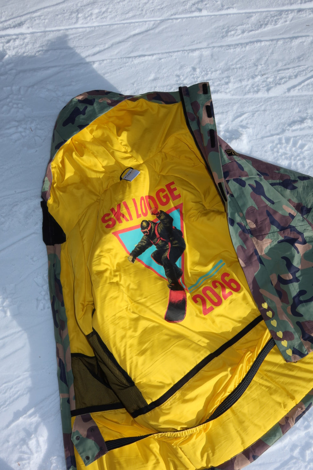 Yellow jacket with camouflage hood and graphics on a white background