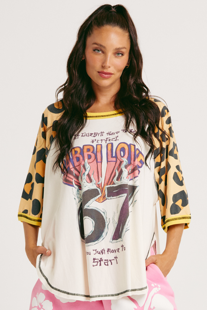 Woman wearing a leopard print sleeve raglan tee with SABBI LOVE 67 in bright lettering 