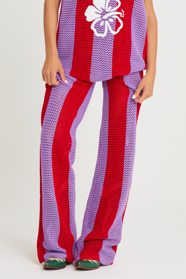 Person standing in photo studio wearing red and purple striped knit pants.